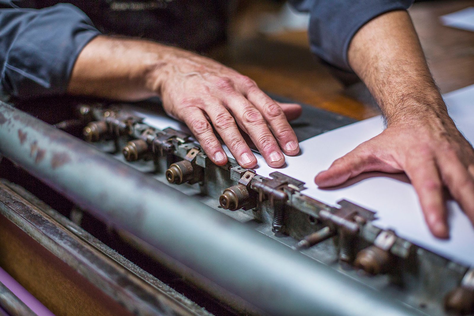 Cropped Image Of Worker Adjusting Paper On Printing Press At Workshop